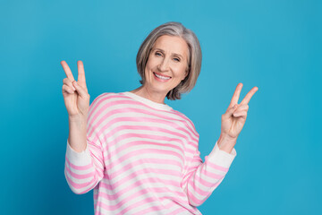 Photo portrait of lovely pensioner lady show v-sign dressed stylish striped garment isolated on blue color background