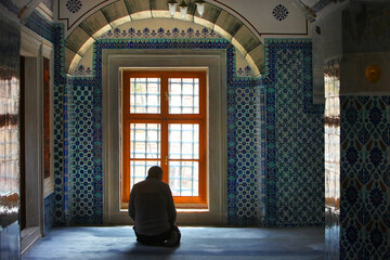 Istanbul,Türkiye, a muslim man sitting and praying in front of the window in the Rustem Pasha...