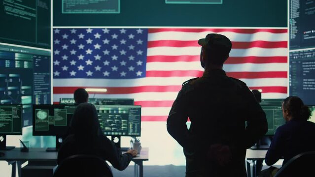 American military personnel ensuring servers protection and classified information, protecting state secrets in high tech agency office. Army soldier supervises hacking activity. Camera B.