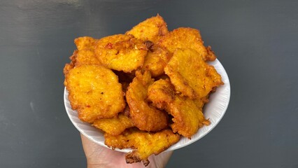 Corn fritters on a plate, plate in hand. dark gray background. Focus selected