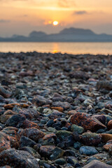 Many rocks on the beach with the background of the sea and mountains with the sunset in the evening and using the blurring technique to take a beautiful picture.