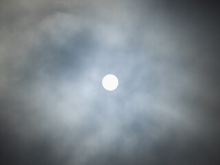 The moon shines in the night sky amidst the clouds and mist.