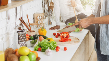 One more happy day together. Smiling african girl mixing salad, cheerful dad cooking dinner, kitchen interior, free space