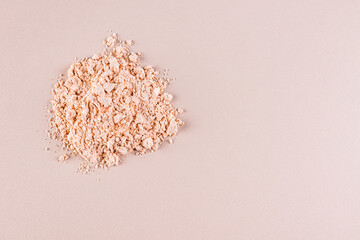 A pile of loose light powder on a beige background. space for text. layout for your product. Color cosmetics texture concept. Top view.