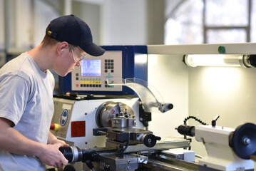young apprentice in vocational training working on a turning machine in the industry