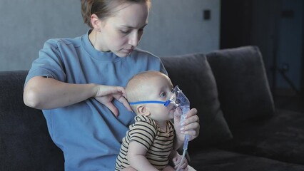 Woman holds up a nebulizer mask to her child's face.