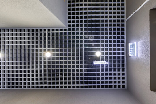 suspended and grid ceiling with halogen spots lamps and drywall construction in empty room in store or house. Stretch ceiling white and complex shape.