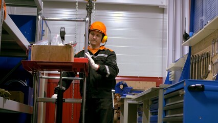 Worker in protective clothing sorting spare parts on factory workshop shelves. Emphasis on organization and safety demonstrates dedication to quality and precision in industrial setting.