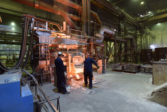 Workers in protective equipment in a foundry during the production of steel components - workplace industrial factory