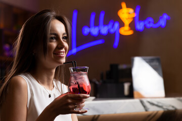 A girl in the lobby bar drinks a cocktail.