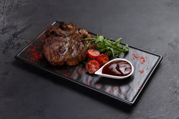 T-bone steak and sauce. On a dark background.