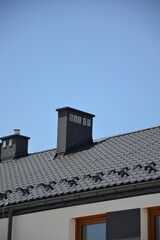 Black roof with chimney on sunny day 