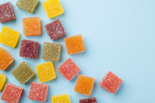 Assorted jelly candies on blue background, top view.