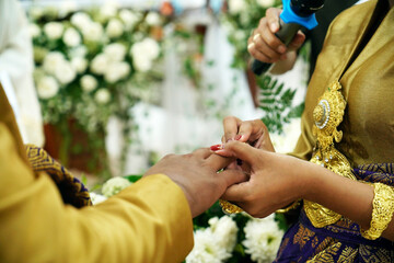 Obraz premium Ring exchange. Balinese bride and groom legalize their marriage by rings exchanging at a catholic wedding mass ceremony in church.