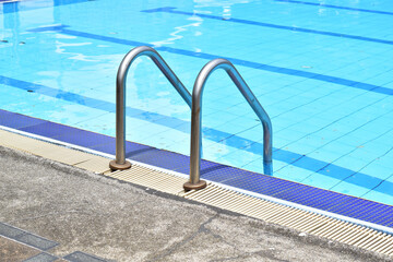 Closeup of Stainless Steel Handrail or Grab bars ladder in the clear blue swimming pool, Concept for convenience in entering the swimming pool at Thailand.