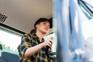 Woman operates agricultural tractor. Photo of a female farm tractor driver.
