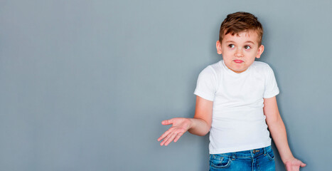 Little cute boy kid wearing casual white t-shirt clueless and confused expression with arms and...