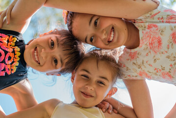 Happy children embracing each other having fun and smiling at camera, group of joyful kids playing together outside.