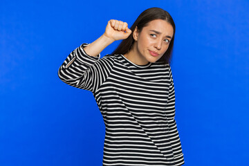 Knock-knock who is there. Confused excited woman knocking door gesture asking who is at home feeling embarrassed, no idea being clueless uncertain. Young girl isolated on blue background. Copy-space