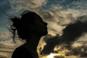 Close up of woman standing while looking at sky with silhouette filter. AIG42.