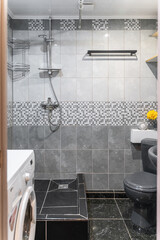 bathroom design with grey white tiles, with grey toilet and sink. The bathroom is decorated in dark...