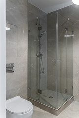 modern bathroom design with light-colored tiles, white furniture and a white toilet bowl. Glass...
