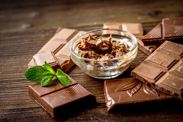 chopped chocolate pieces with mint for dessert wooden desk background