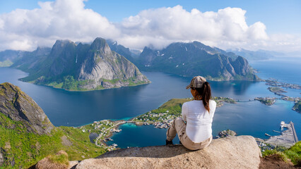 A lone traveler enjoys the breathtaking view from a mountaintop overlooking the turquoise waters...