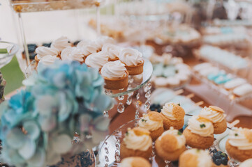 sweet bar with muffins cakes and sweets in area of wedding party. Wedding dessert table with delicious cakes