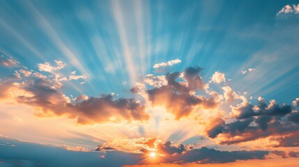 Fototapeta premium Hopeful sunrise nature background of dramatic blue sky and vibrant orange sun rays emerging from the clouds.
