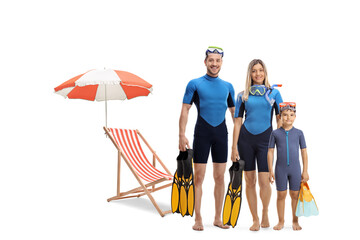 Full length portrait of a family in wetsuits, holding diving flippers and posing next to a beach chair © Ljupco Smokovski