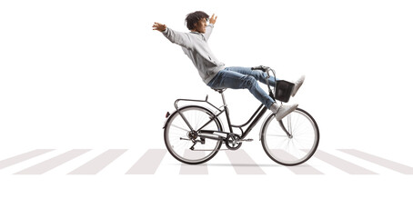 Obraz premium Young african american man riding a bicycle with arms up at a pedestrian zebra crossing