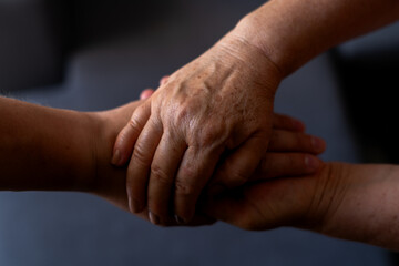 Fototapeta premium Close-up of a mother and her adult son clasping hands, symbolizing their deep connection, love, and support