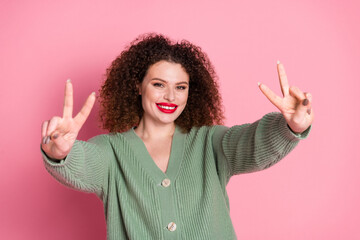 Photo of cheerful good mood woman wear stylish khaki clothes demonstrate v-sign isolated on pink color background