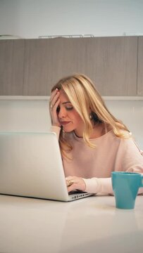 Vertical hard working woman, desperate due to laptop issues causing her stress and headaches. A frustrated and burnout female dealing with excessive work that triggers anxiety and migraines problems