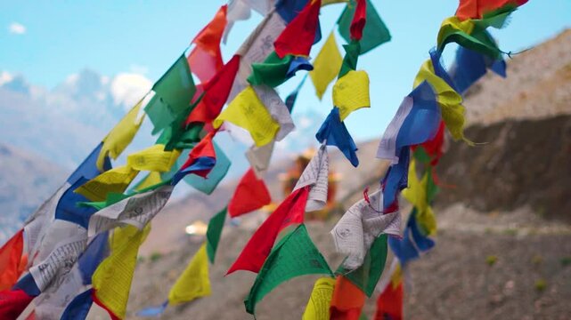 Slow motion shot of colorful Tibetan Buddhist prayer flags waving in front of the Gue Monastery in Spiti Valley, Himachal Pradesh, India. Prayer flags in front of the monastery in India.