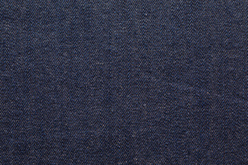 A close-up view of the texture of dark blue denim fabric.