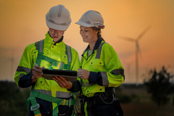 Team Engineers men and woman checking and inspecting on construction with sunset sky. people operation. Wind turbine for electrical of clean energy and environment. Industrial of sustainable.