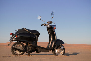 The Retro black scooter at sunset in the golden sand of the Namib Desert