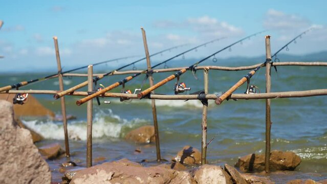 A wooden fishing pole with a few rods attached to it. The rods are in the water and the water is choppy