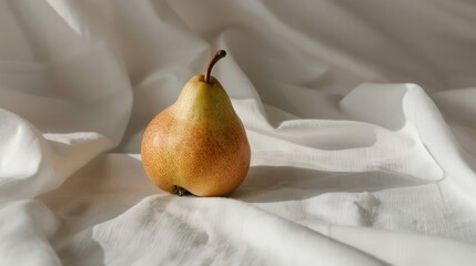 Minimalist fashion still life featuring a fresh pear on white fabric backdrop