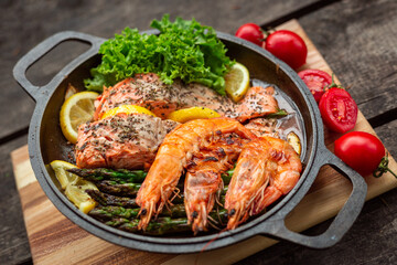 Healthy baked salmon steaks with greens and asparagus in a black cast iron skillet. A delicious low-carb breakfast.