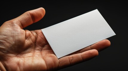 Obraz premium Hand holding blank business card, close-up shot. Networking and professional identity concept