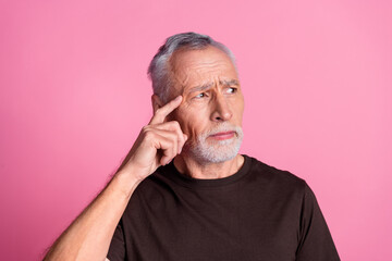 Portrait of minded man with white gray beard dressed brown t-shirt look empty space finger on head...
