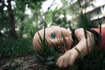 Creepy doll with scary blue eye lies on the ground