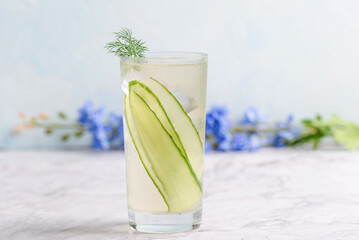 A glass of cold cucumber non-alcoholic mocktail with ice and garnished with dill.
