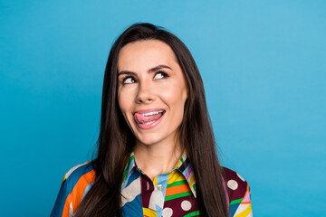 Fototapeta premium Photo of pretty young girl look interested empty space lick teeth wear trendy colorful print outfit isolated on blue color background