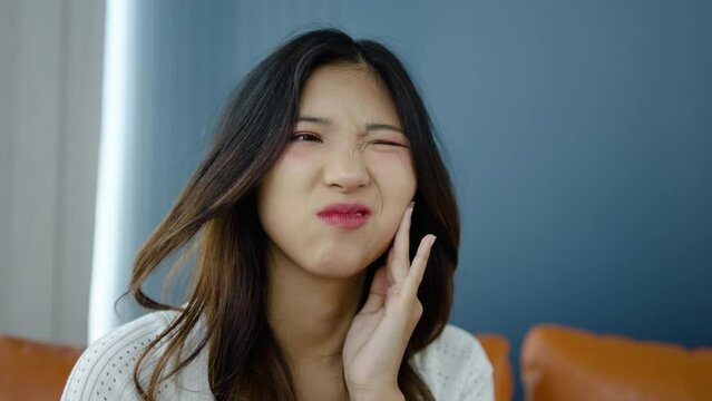 Toothache, Upset young asian woman touch cheek, suffers from toothache, girl having terrible sudden tooth pain at home, need dental treatment, pulpitis, gum disease concept, Health care and dental