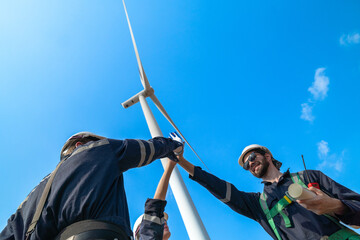 The engineering team joins hands with confidence after completing the inspection of the wind turbine construction site to produce clean electricity and help with sustainability and reduce pollution.