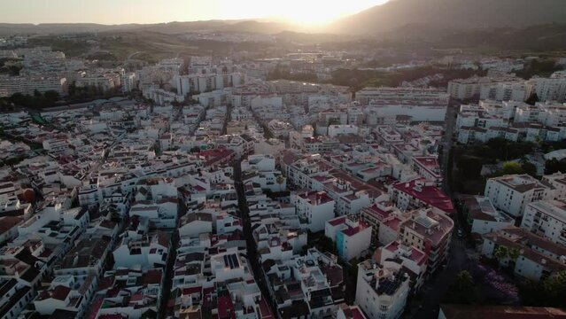 Capturing an aerial view of a Mediterranean town during sunset against an urban landscape backdrop
